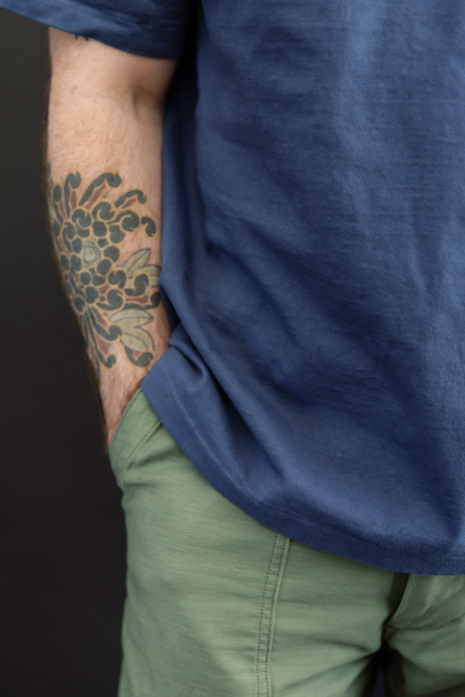Close-up side view of navy tee hem and olive shorts on male model, 5'9