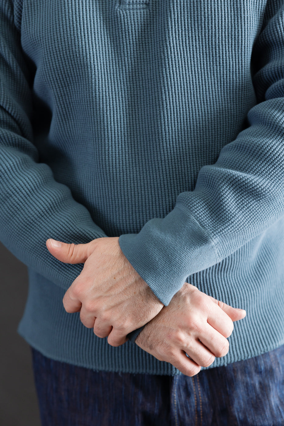 Close-up, front view of Studio D'Artisan blue heavy thermal Henley on male model, showing textured fabric and sleeves, 5'9