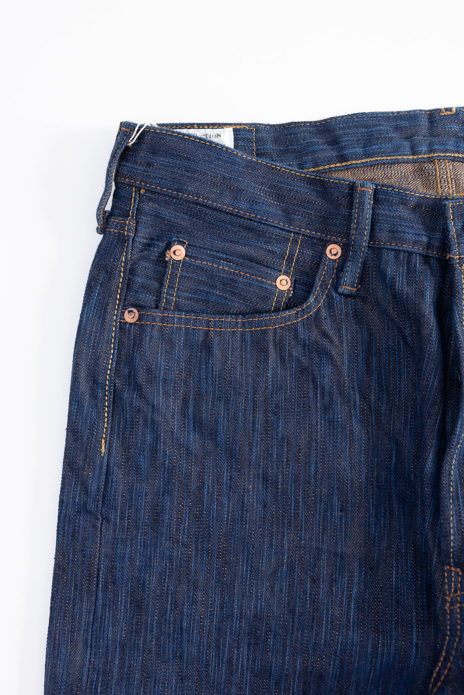 Close-up of Studio D'Artisan 15oz selvedge jeans front upper left, natural indigo texture, pocket and rivet details