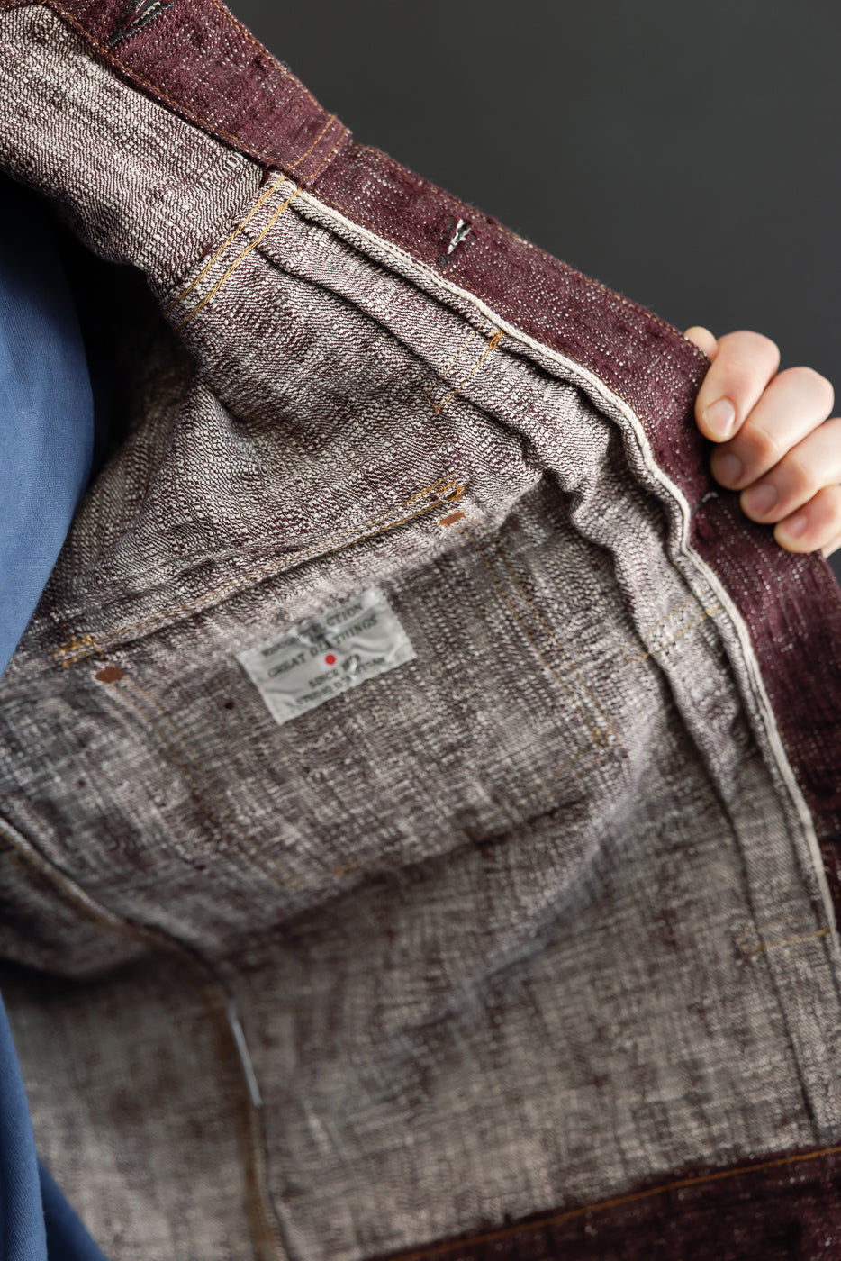 Close-up of selvedge denim jacket interior, showing fabric texture, stitching, and brand tag detail