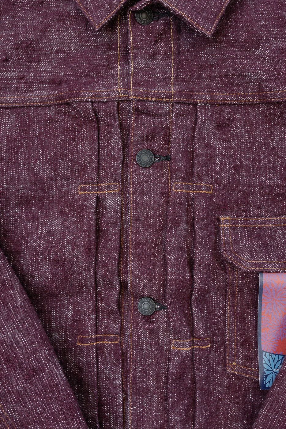 Close-up front view of burgundy selvedge shirt with contrast stitching, button placket, and chest pocket detail