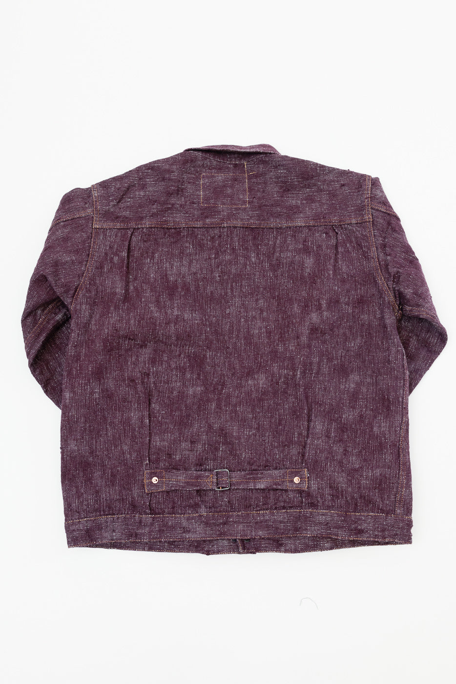 Back view flat lay of dark purple selvedge denim jacket with waist adjuster, showing fabric texture and stitching details