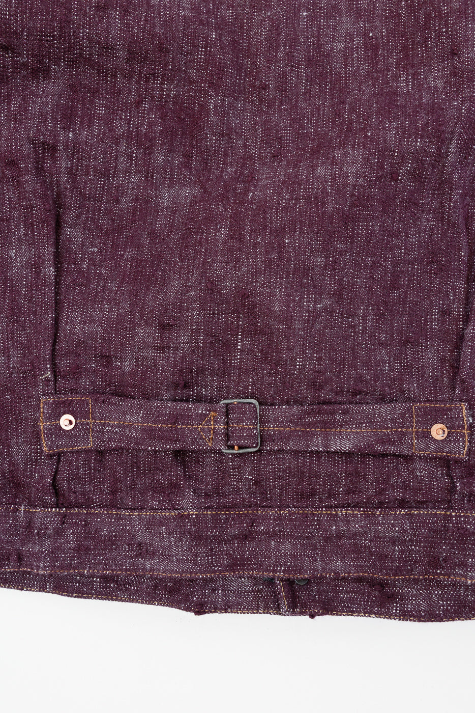 Close-up front view of deep purple selvedge shirt waistband with metal buckle, copper rivets, and contrast stitching