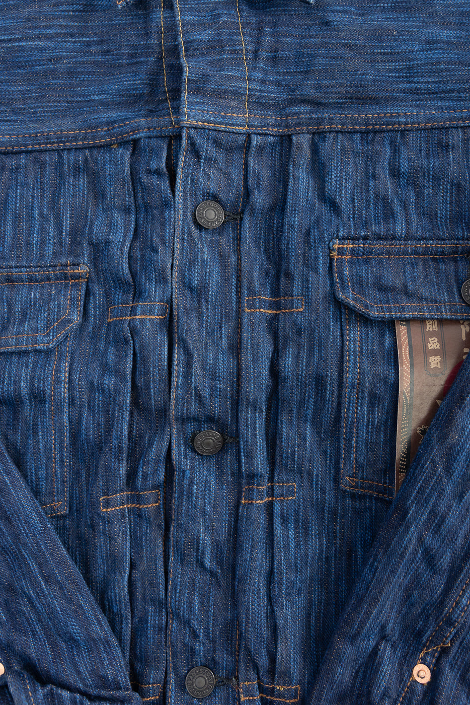 Close-up of front chest area on natural indigo selvedge Type II jacket, showing buttons, fabric texture, and chest pocket flaps.