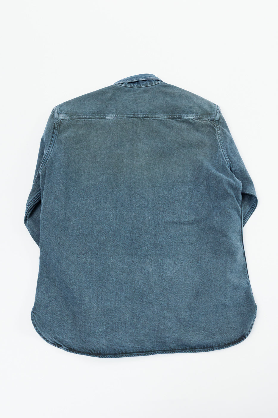 Flat lay back view of a blue denim button-down shirt with a curved hem.