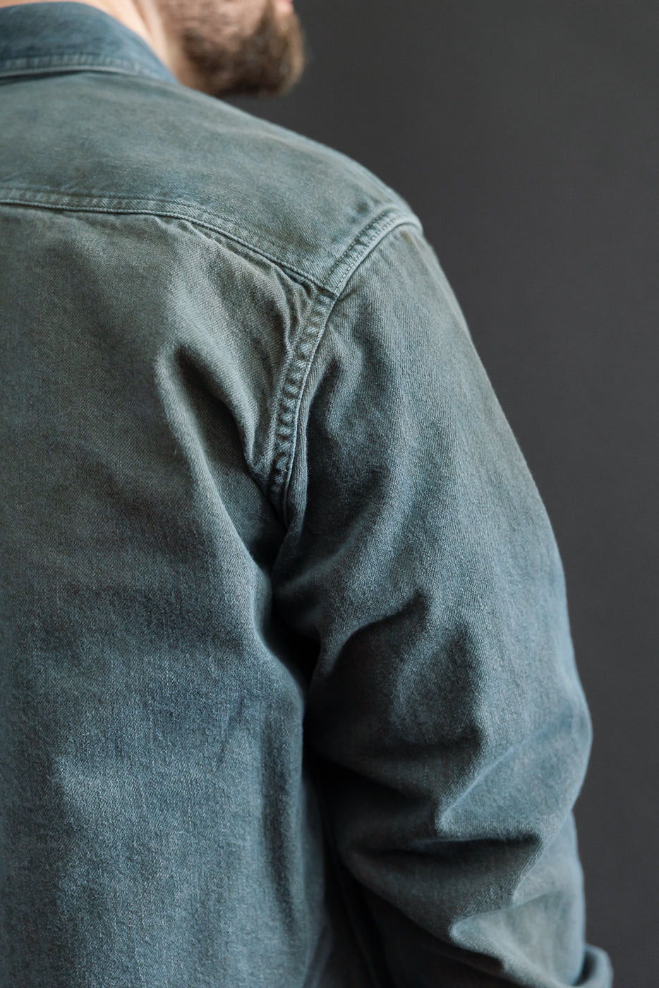 Close-up back view of a blue denim shirt on a male model, 5'9
