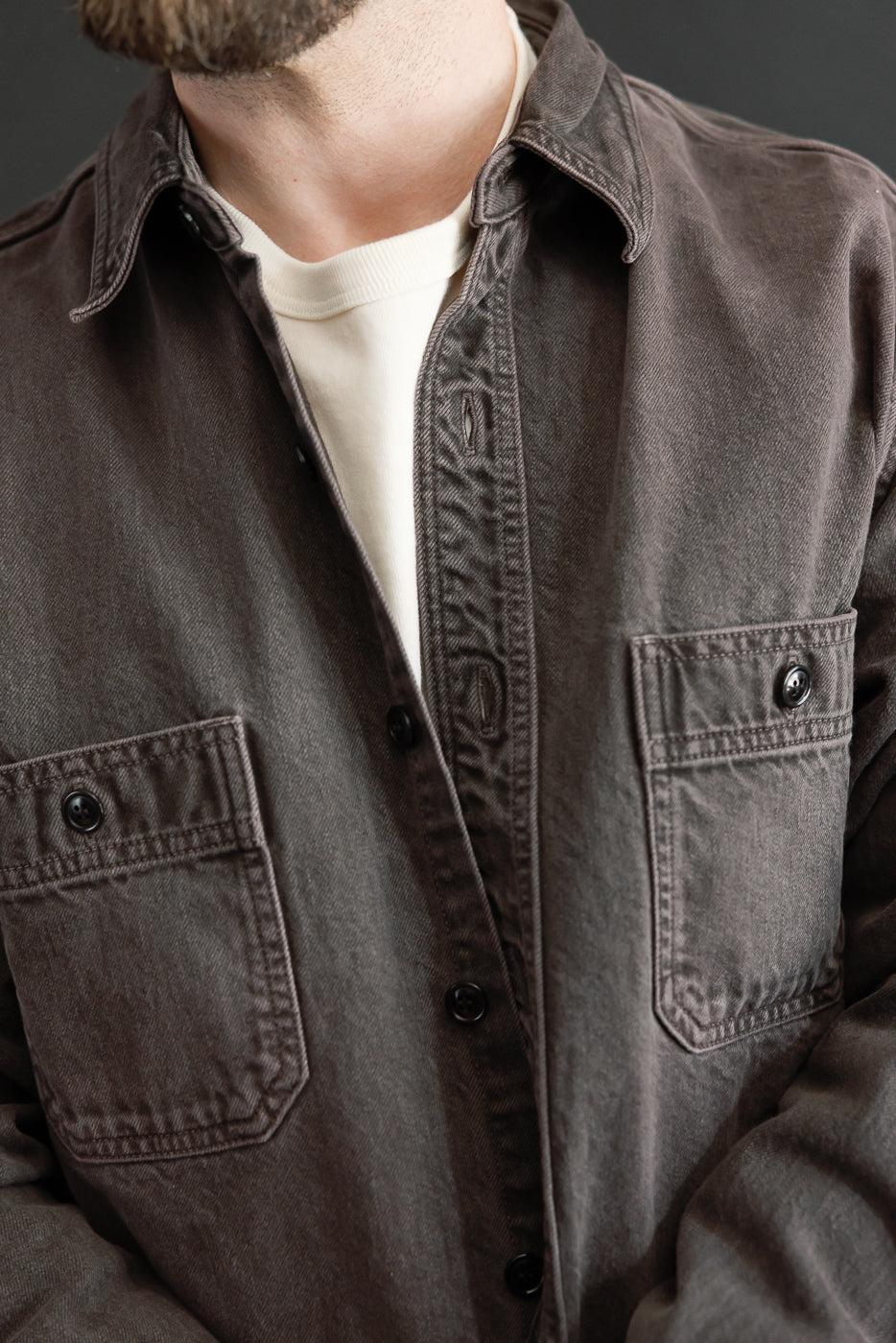 Close-up front view of a male model wearing a brown button-down shirt with chest pockets.