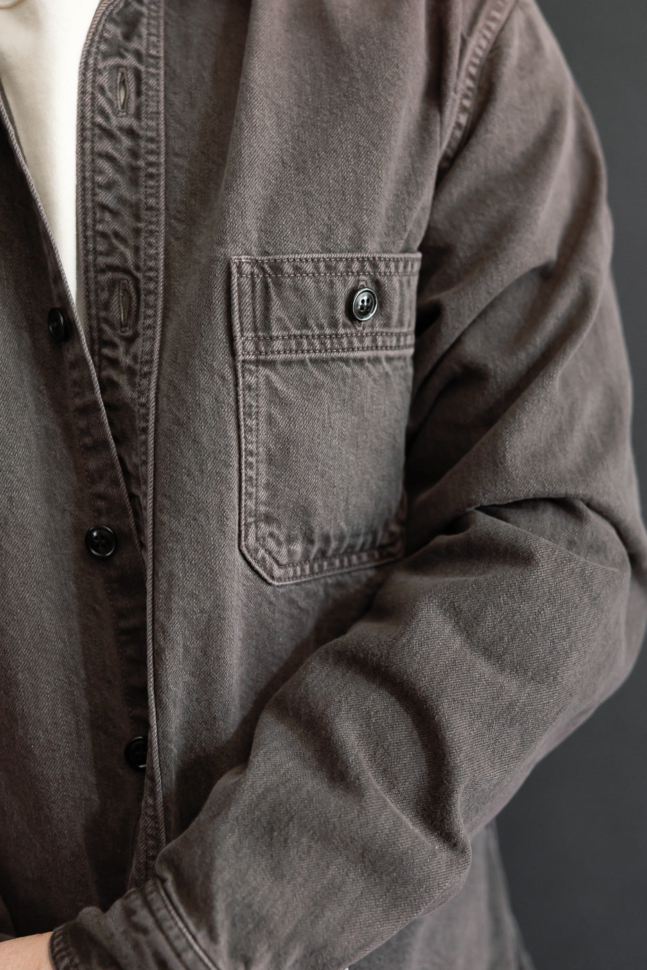 Close-up of front chest and sleeve of a brown button-down on a male model, 5'9
