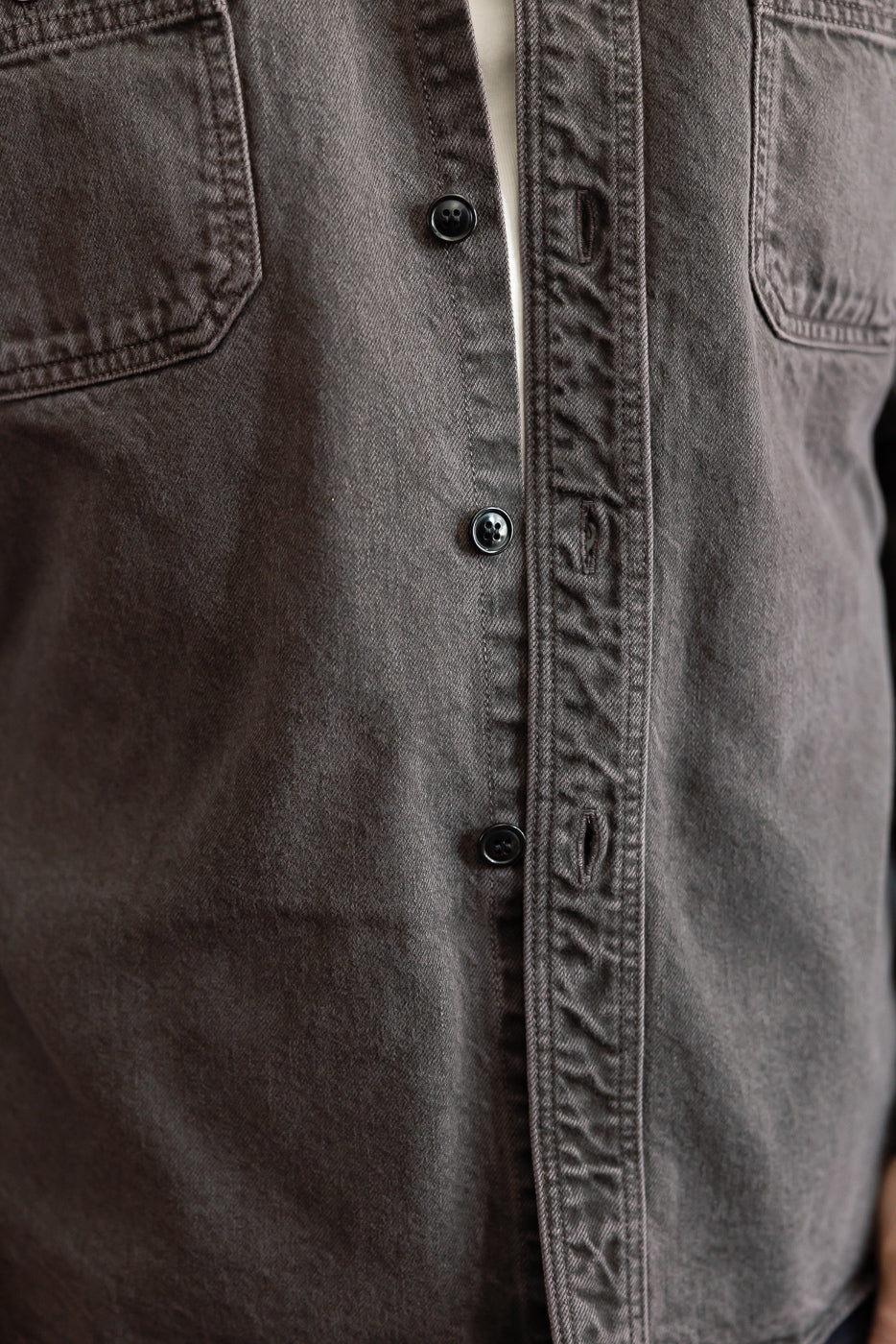 Close-up of the front of a grey button-down shirt on a male model, 5'9