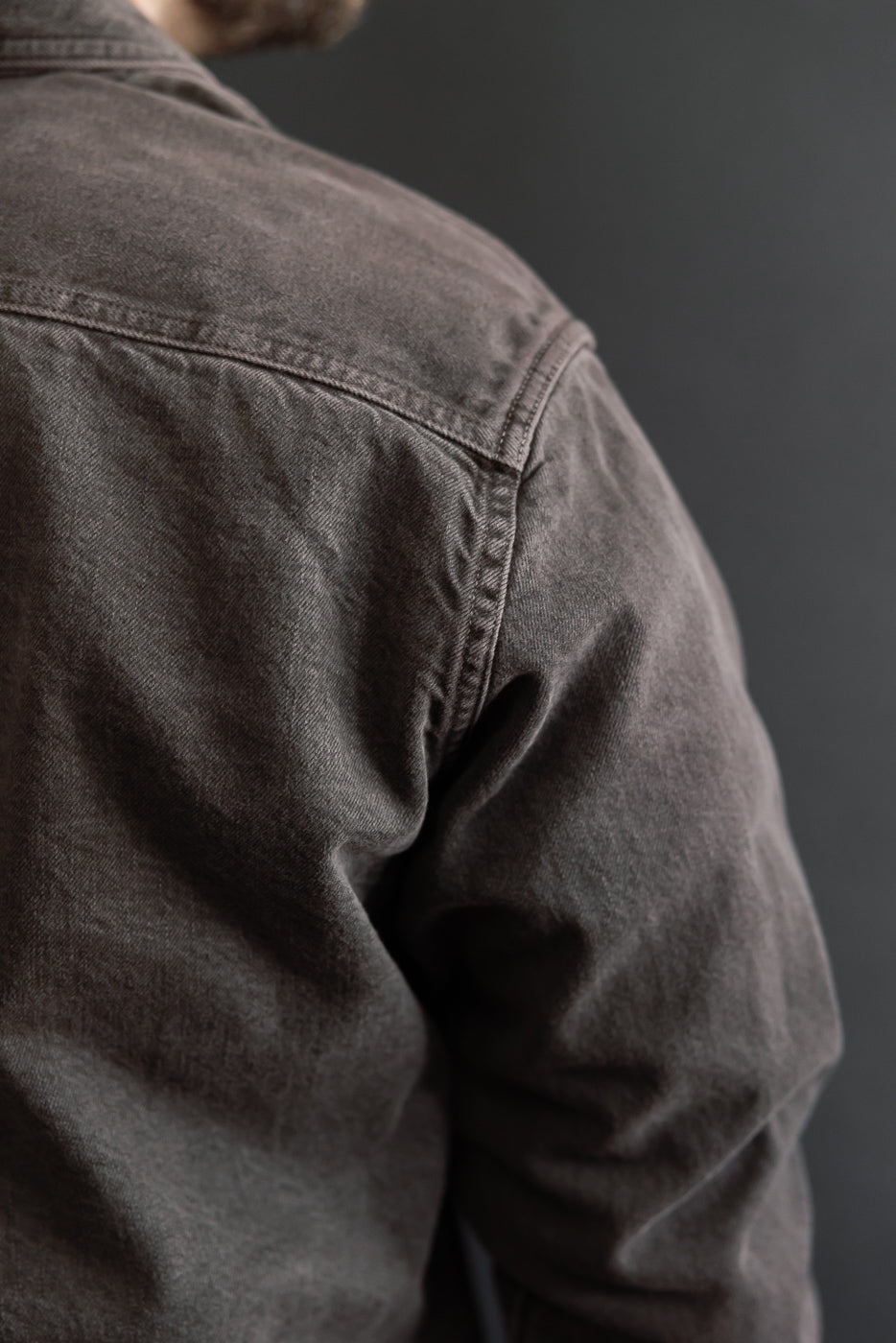 Close-up of the back and shoulder of a brown jacket on a male model, 5'9