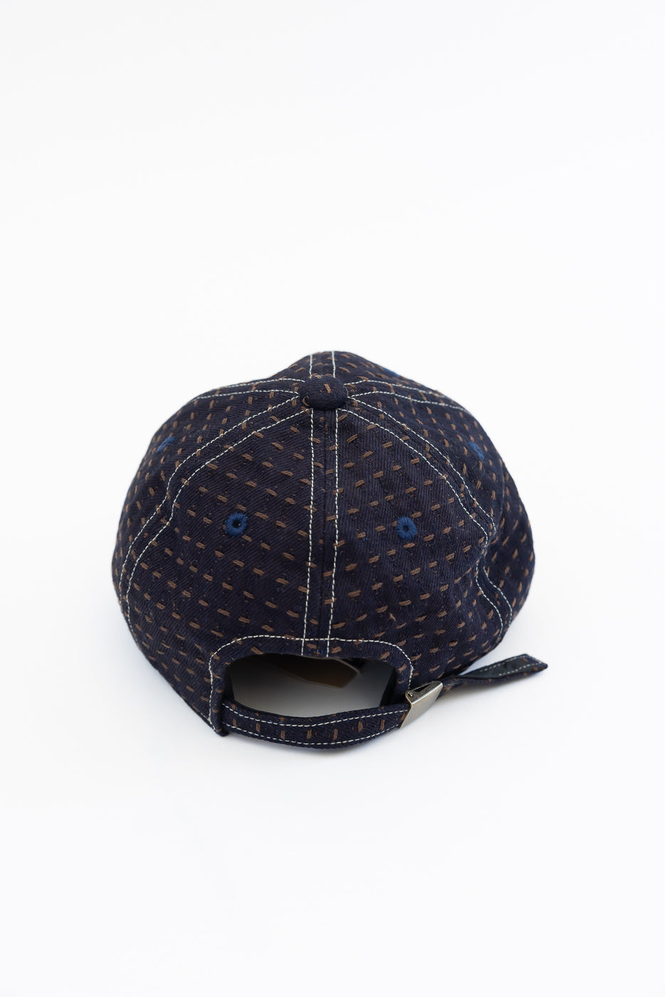 Back view of navy cap with dotted pattern, white stitching, and adjustable strap