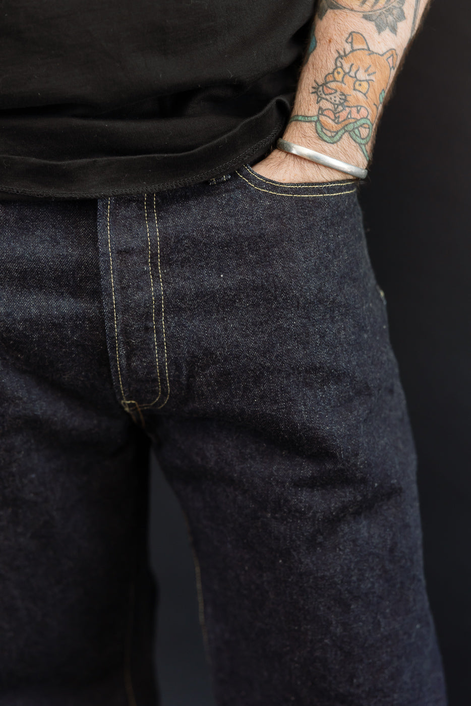 Close-up front view of dark selvedge denim jeans on male model, 5'9