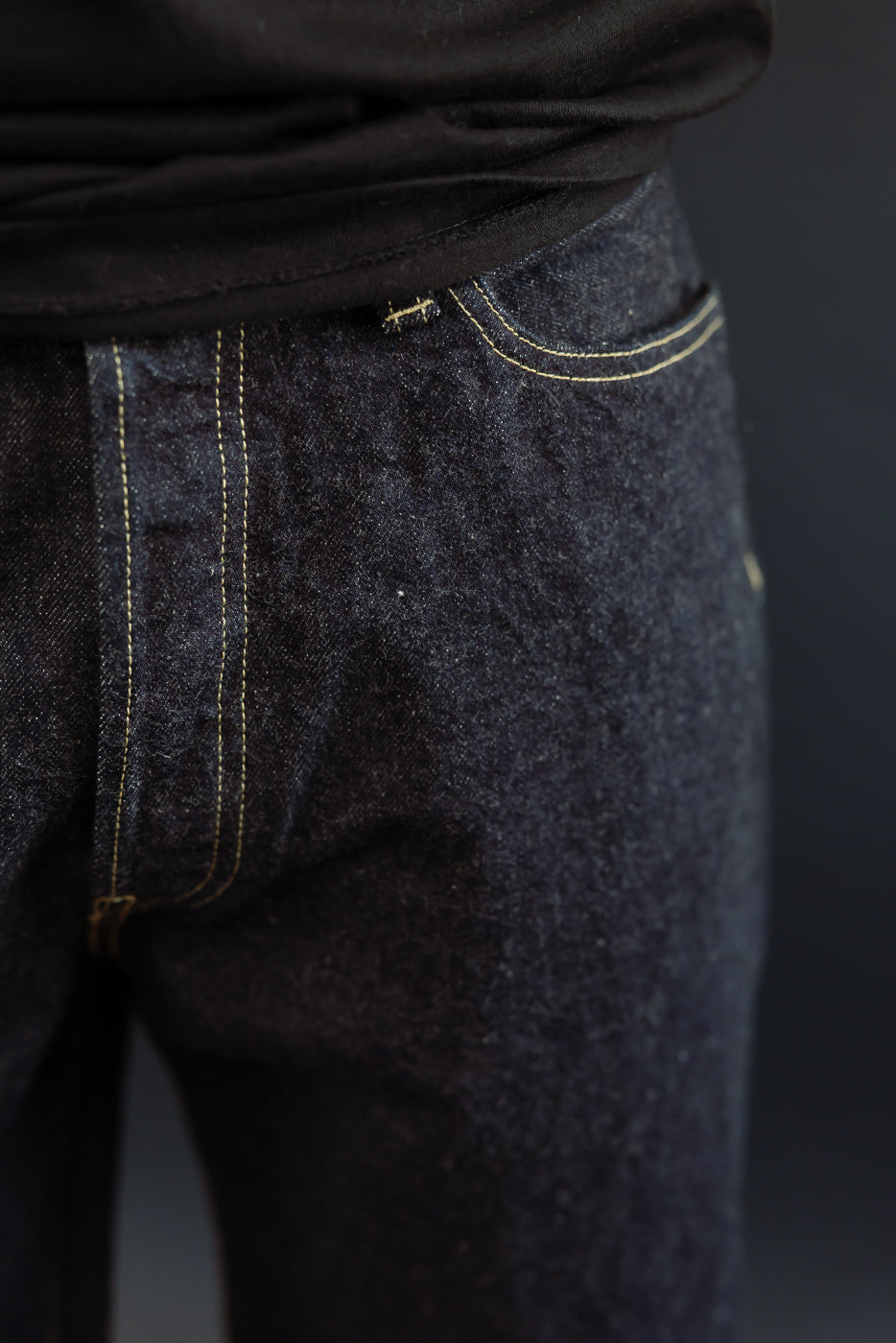 Close-up front view of dark selvedge denim jeans on male model, 5'9