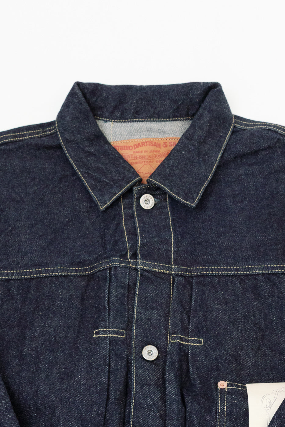 Close-up front view of dark selvedge denim shirt, showing collar, buttons, and Studio D'Artisan tag detail.