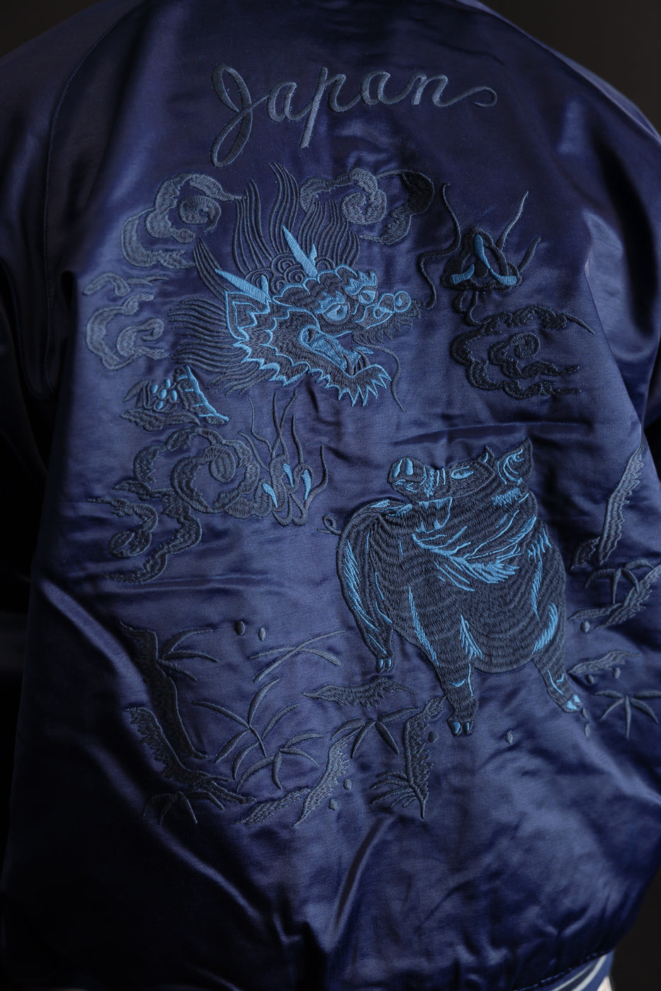 Close-up of back of indigo-dyed sukajan jacket, dragon and boar embroidery, on male model