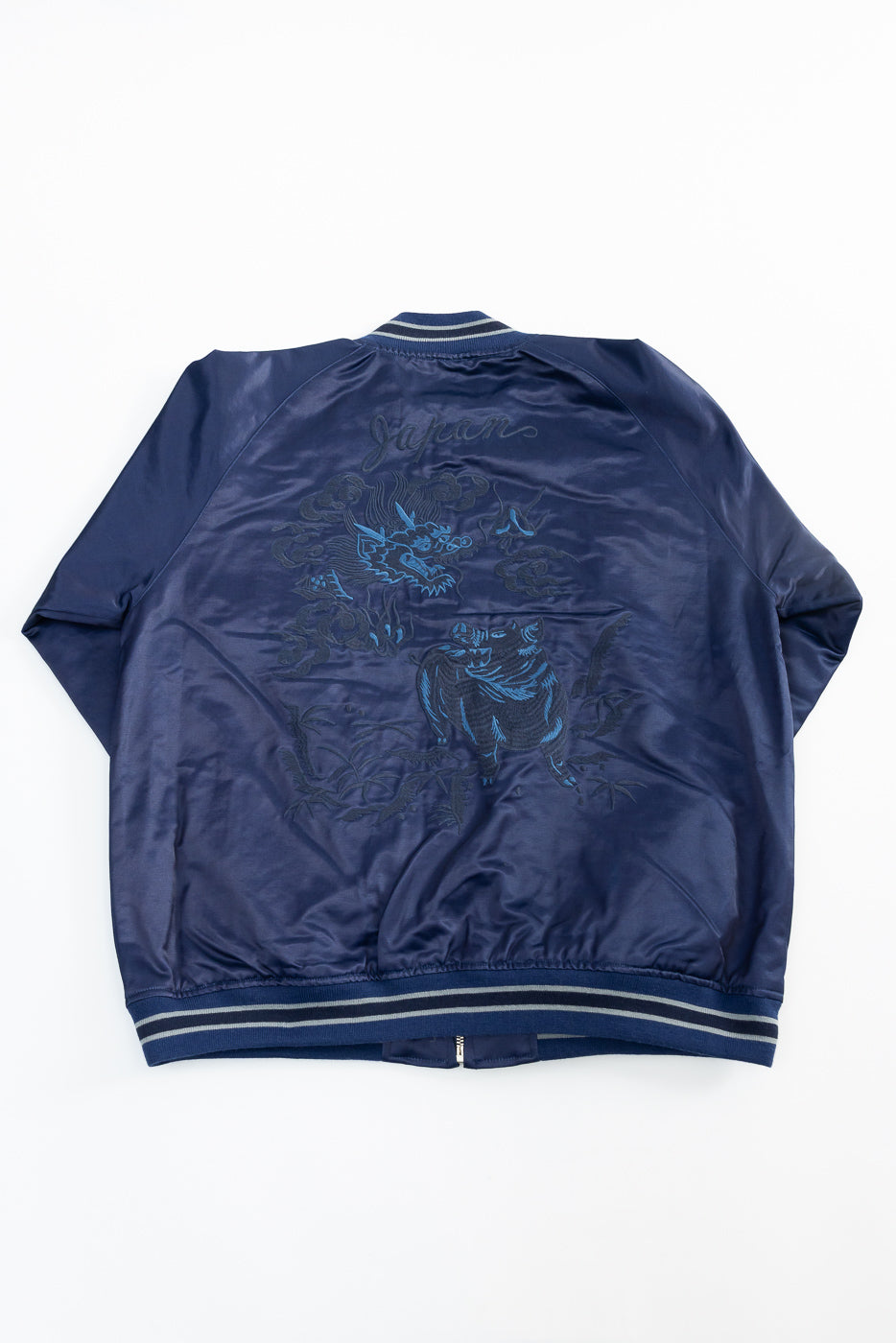 Flat lay back view of indigo sukajan jacket with dragon and boar embroidery details.