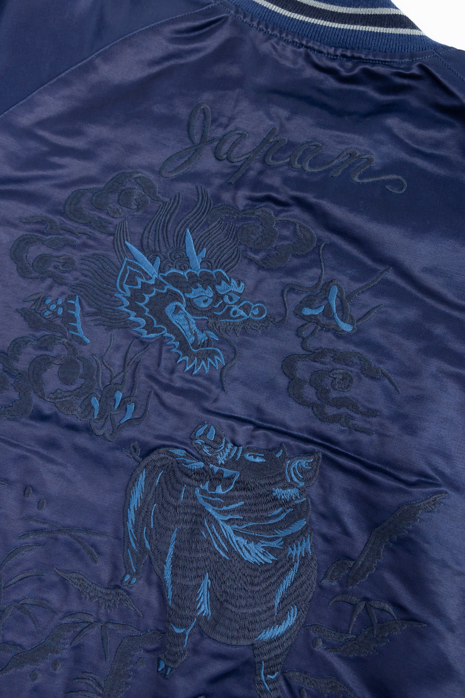Close-up of back of indigo sukajan jacket showing dragon, boar, and cloud embroidery details.