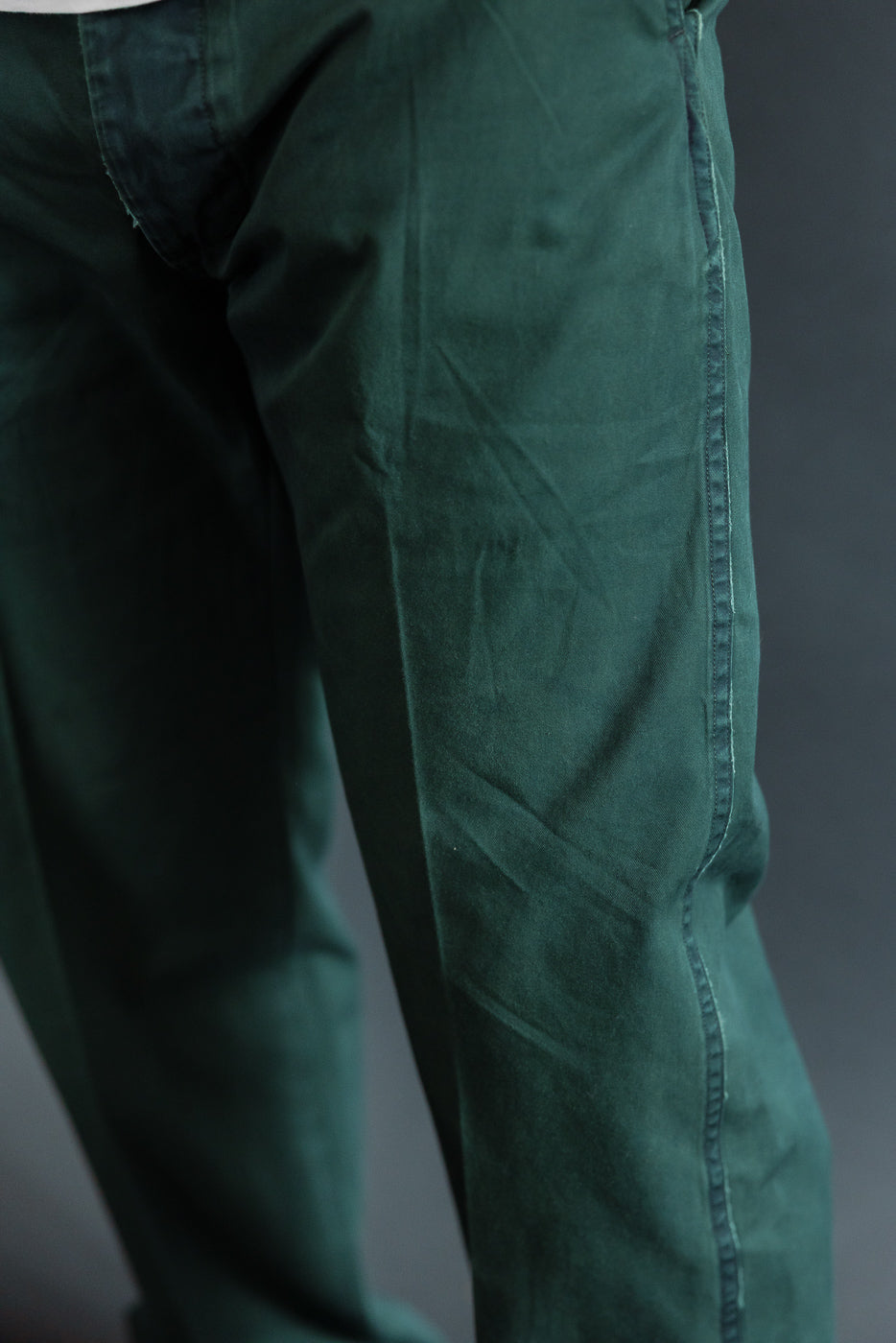 Close-up side view of dark green casual pants on male model, showing fabric texture and stitching detail