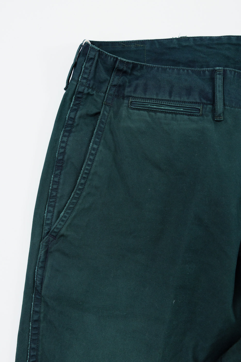 Close-up front view of dark green casual pants, showing waistband, belt loop, and front pocket detail