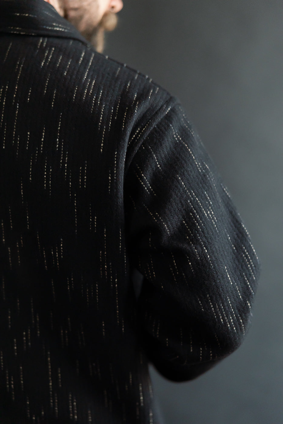 Close-up of back and shoulder detail on Studio D'Artisan Kasuri-dyed black coverall, worn by male model 5'9