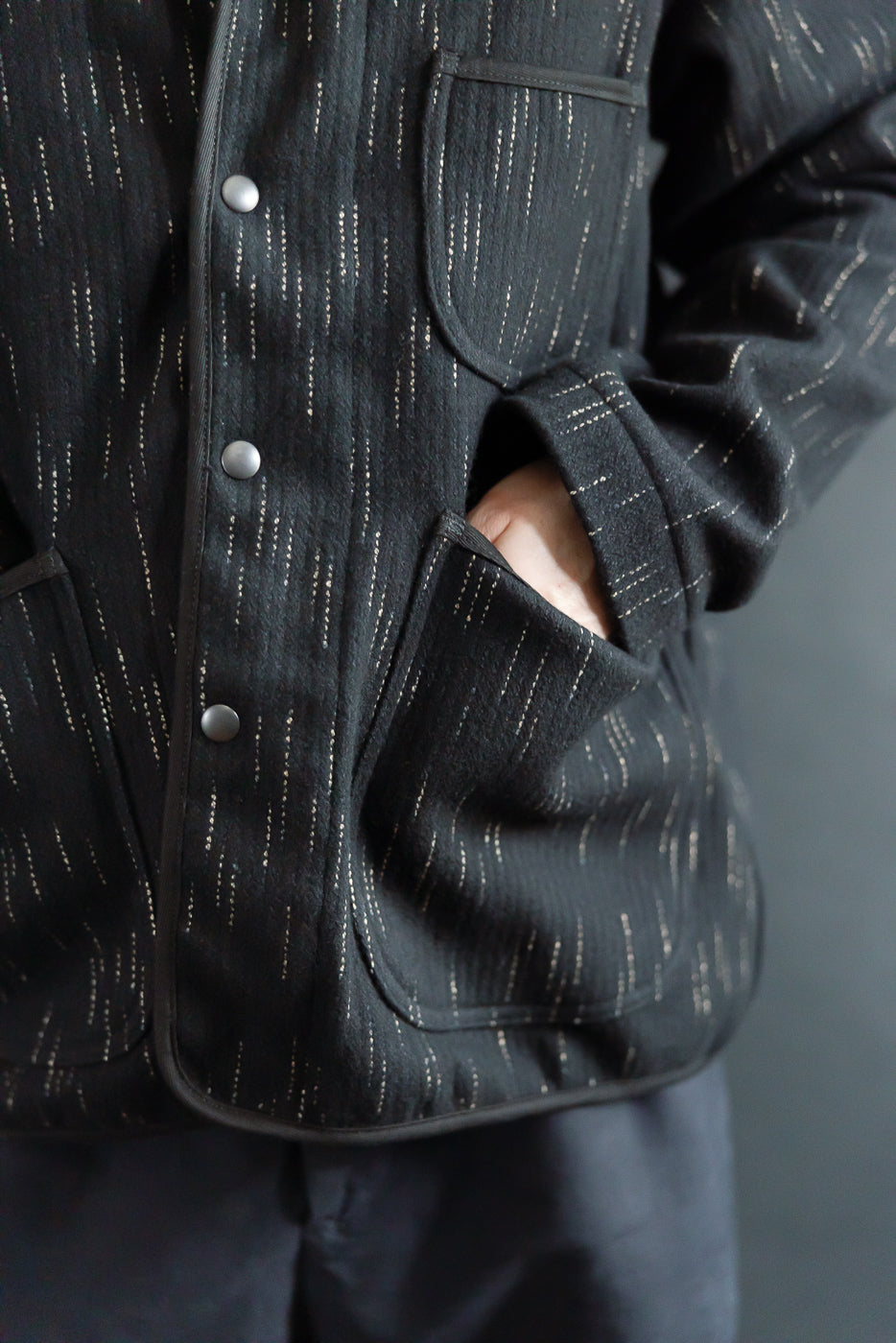 Close-up front view of Studio D’Artisan Kasuri-dyed black coverall, pocket, and snap buttons, worn by male model 5'9