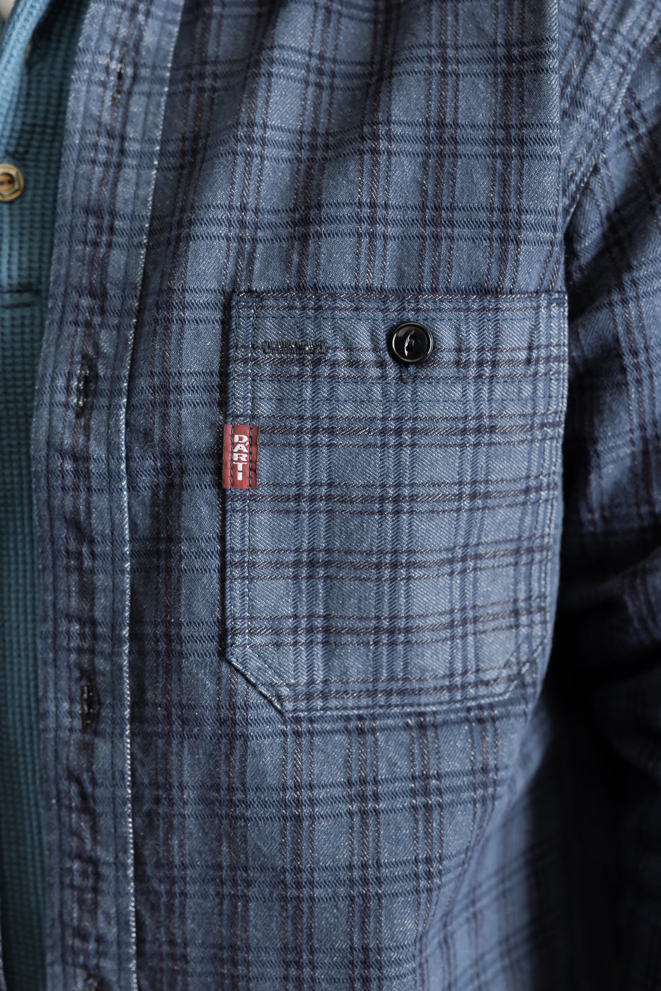 Close-up of men's 13oz jacquard check work shirt front chest pocket, button, DANT tag, navy plaid detail
