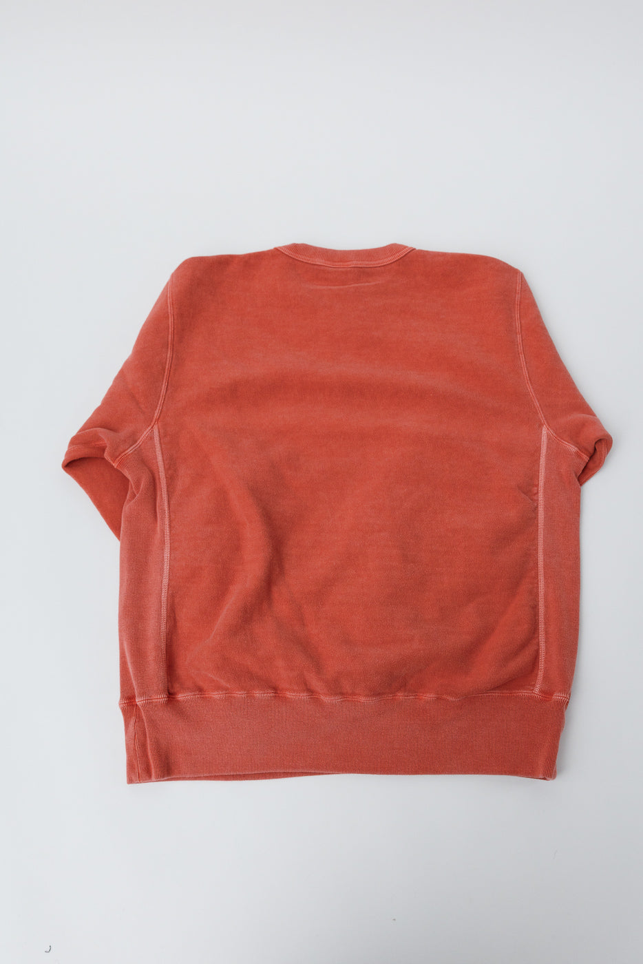 Flat lay of Studio D'Artisan red Bengara reverse weave sweatshirt, back view, showing hem and seams.