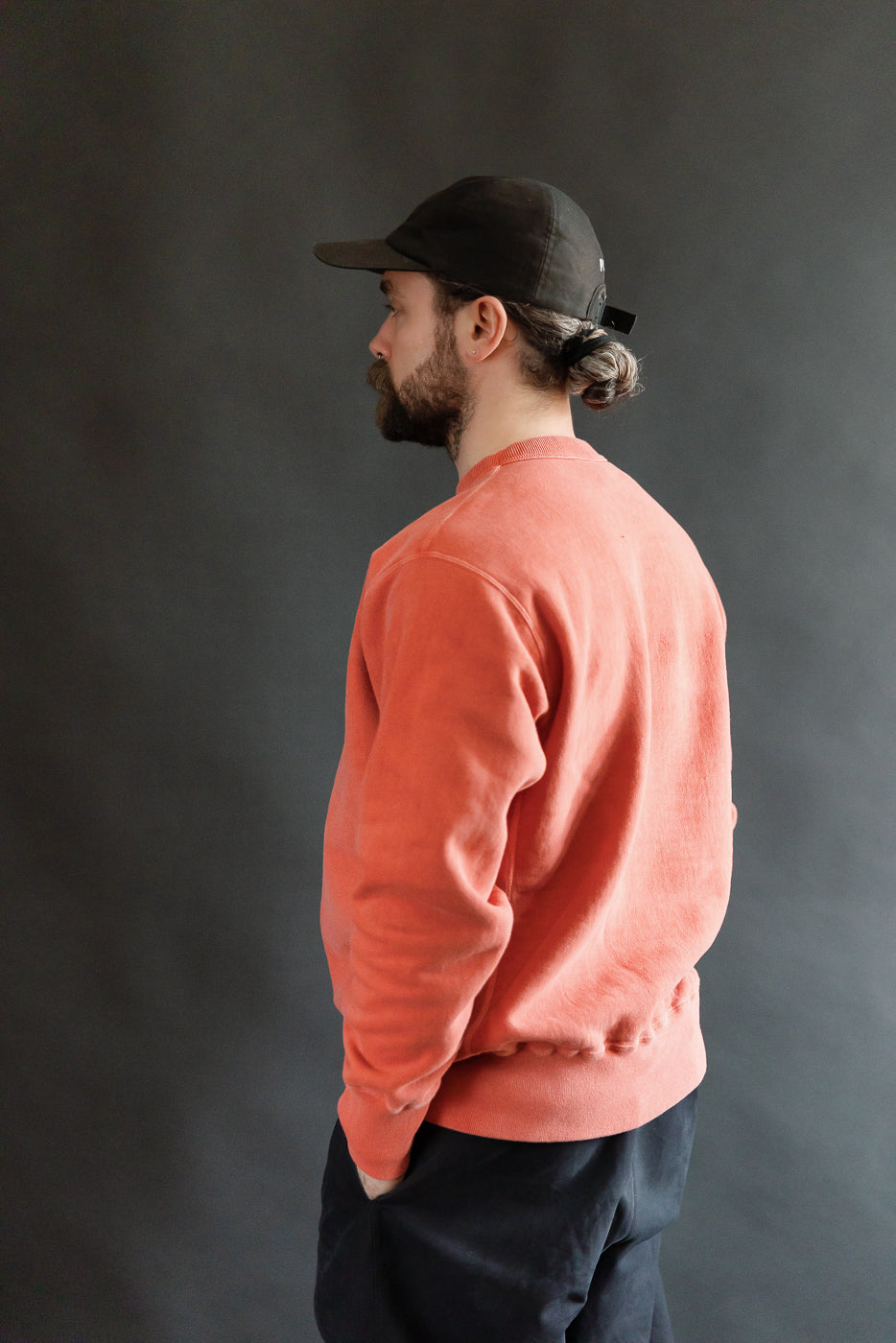 Male model 5'9 165lbs athletic build wearing red Studio D'Artisan reverse-weave sweatshirt, left rear side view, ribbed hem and cuffs visible, casual apparel from Dant.