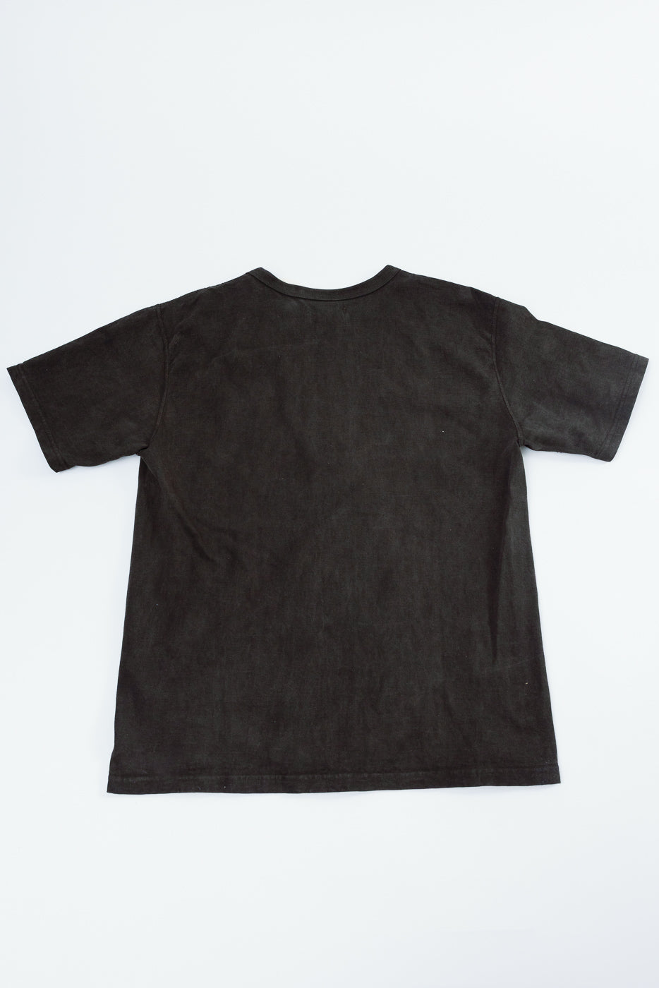 Back view of black short-sleeve t-shirt, flat lay, showcasing hem and fabric texture