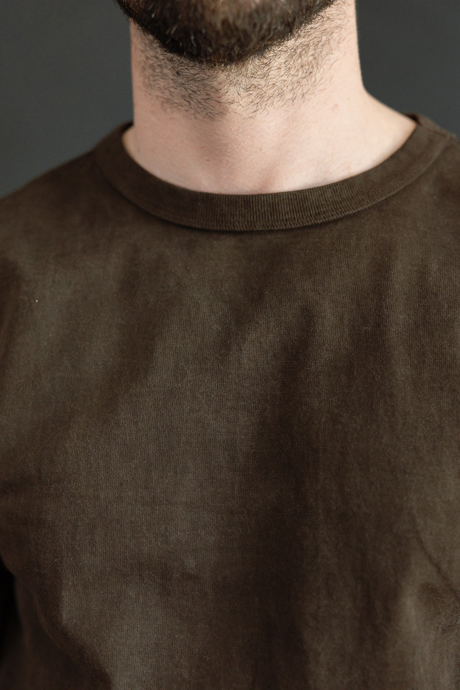 Close-up front view of olive crewneck tee, male model, athletic build, ribbed collar detail