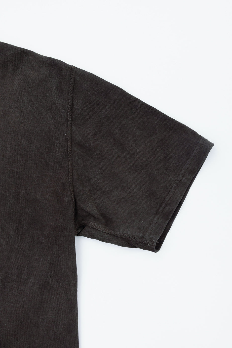 Close-up of black t-shirt sleeve, showing hem and fabric texture, front view