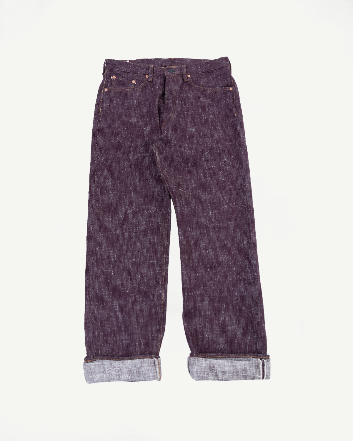 Front flat lay of dark selvedge denim jeans with cuffed hems, copper rivets, and visible stitching
