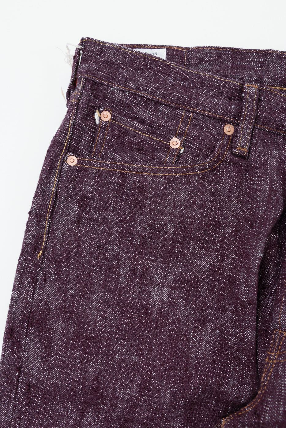 Close-up front view of dark selvedge denim jeans with copper rivets and stitching details