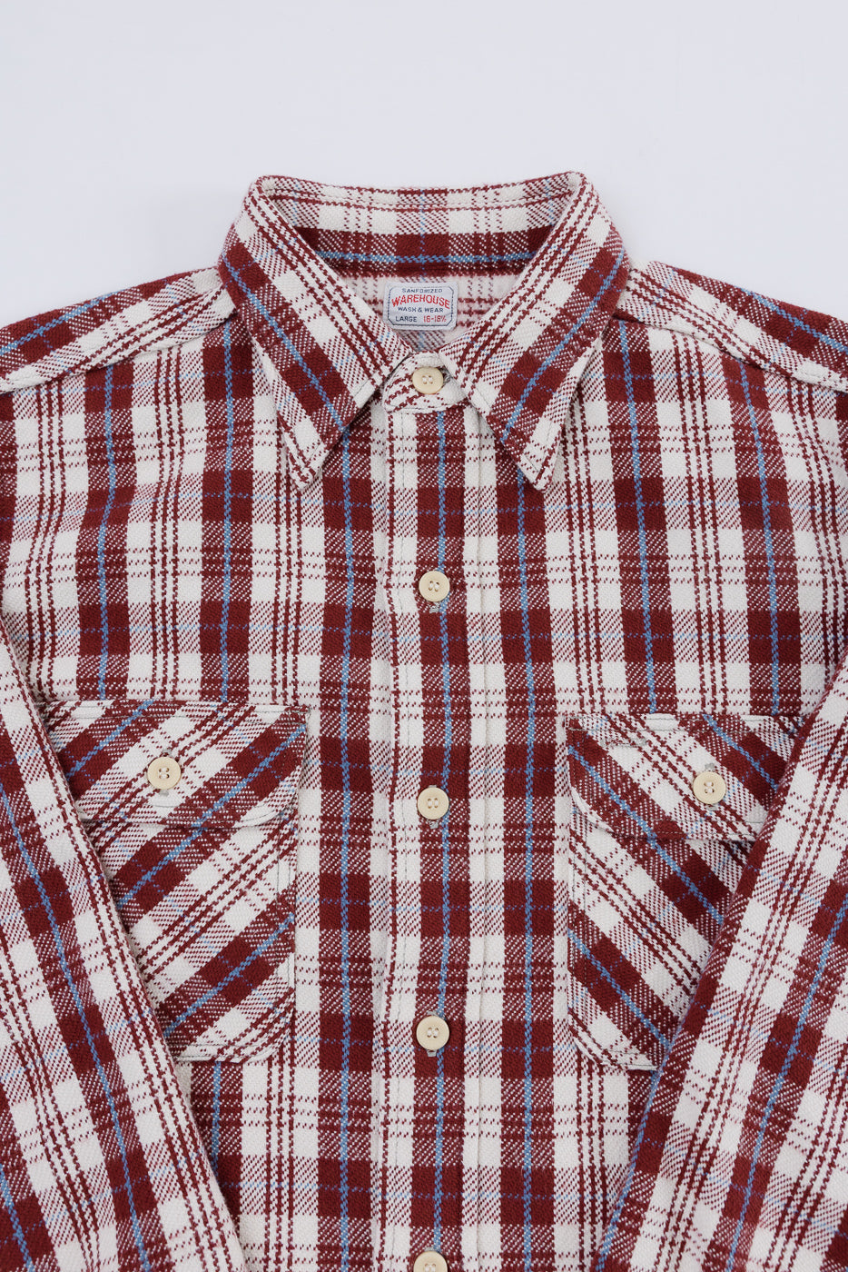 Close-up front view of maroon plaid flannel shirt showing collar, button placket, and chest pockets