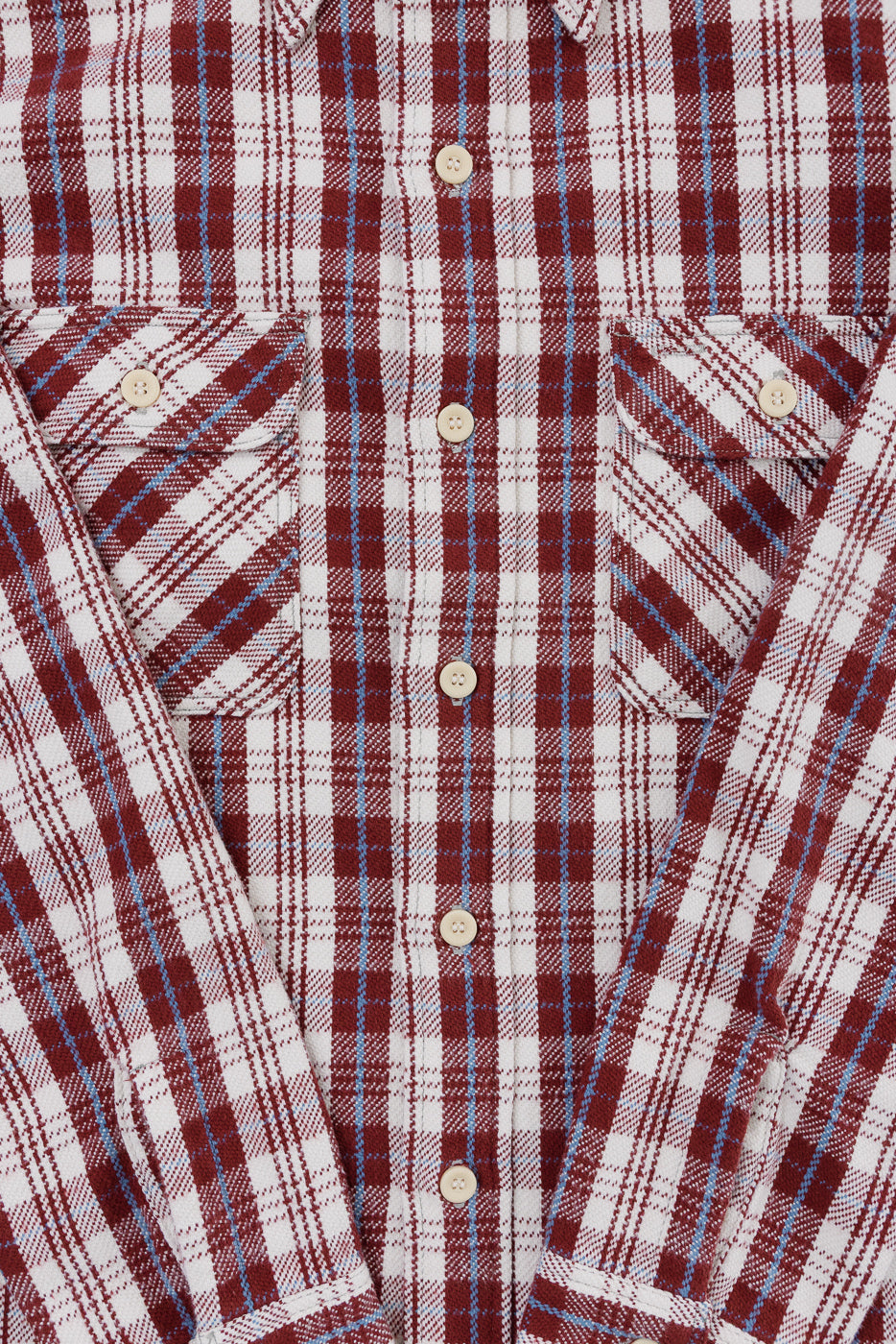 Close-up front of maroon and white plaid flannel shirt showing buttons, chest pockets, and fabric texture
