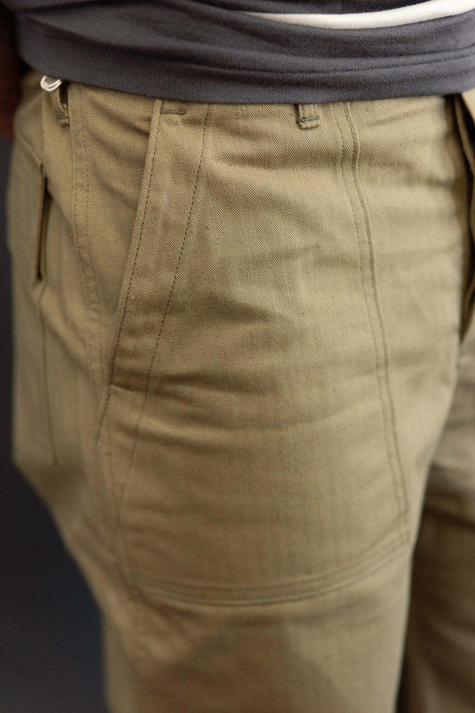 Close-up of male model's front, olive cargo pants with textured fabric and visible stitching details