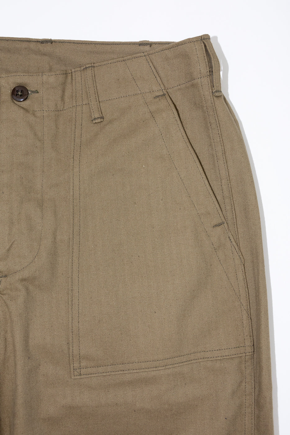Close-up front view of khaki cargo pants showing button, pocket stitching, and fabric texture