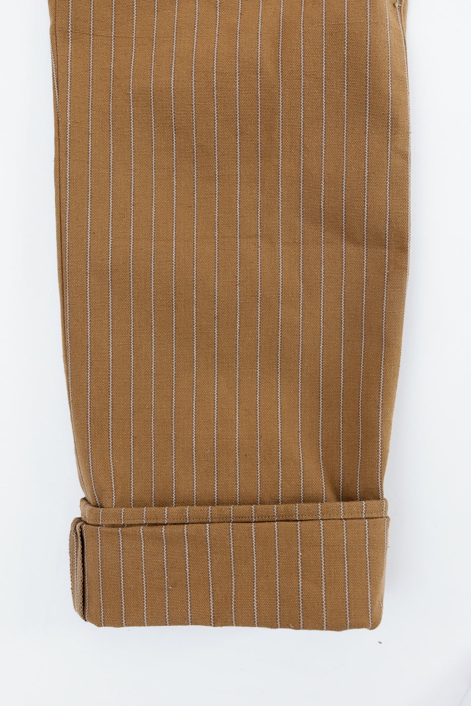 Close-up of front leg hem of duck stripe trousers showing pinstripe fabric texture and thick cuff.