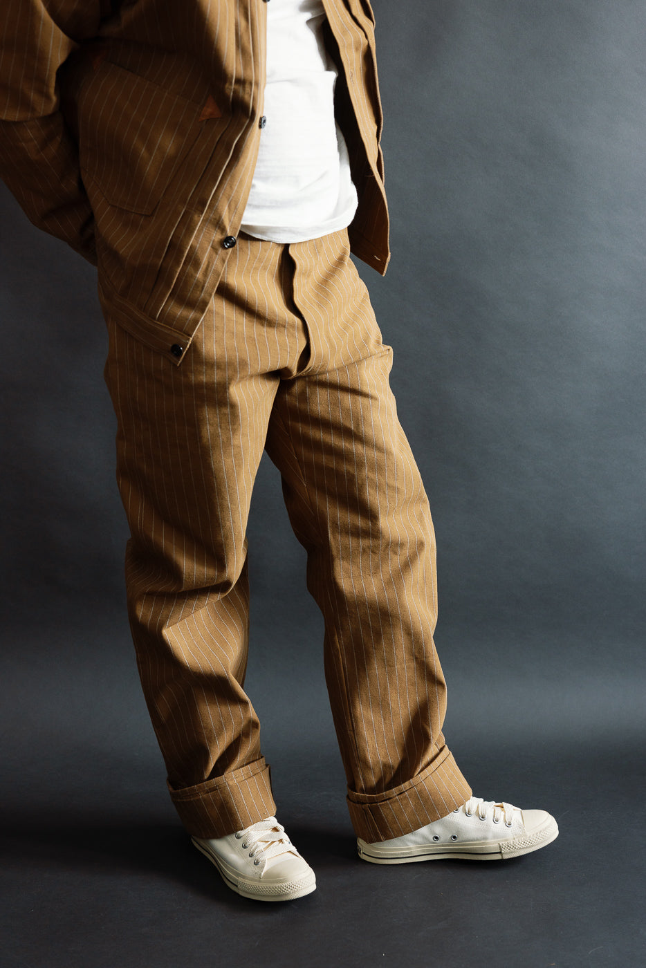 Full body front view of brown pinstripe overall trousers on male model, 5'9