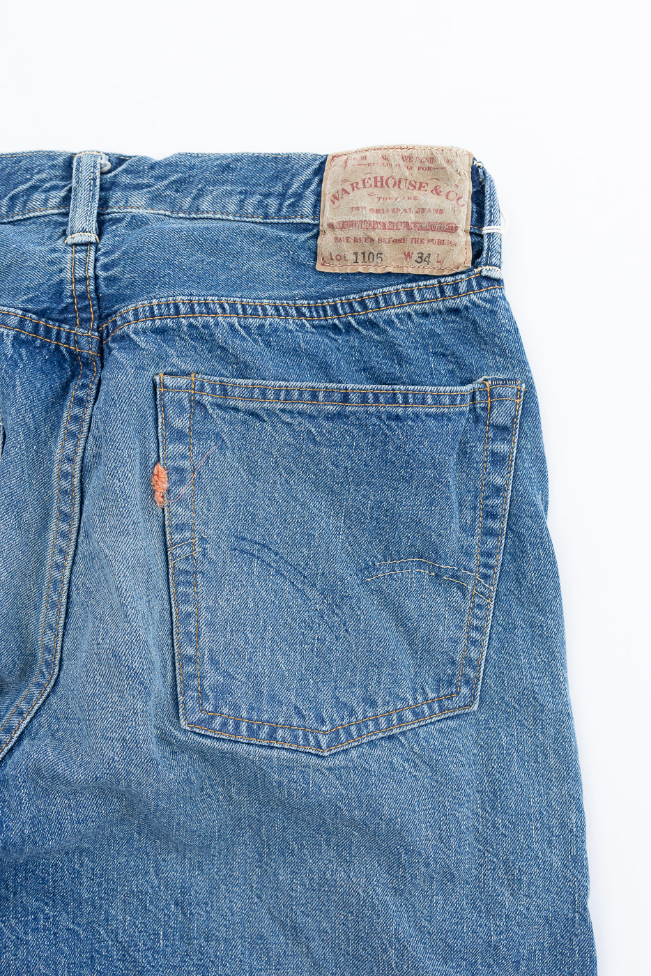 Back view of Lot 2nd-Hand 1105 - 12oz Used Washed Indigo Denim - Tapered Fit jeans, showing faded indigo denim, orange topstitching on rear pocket, and leather brand patch. Distressed spot near pocket.
