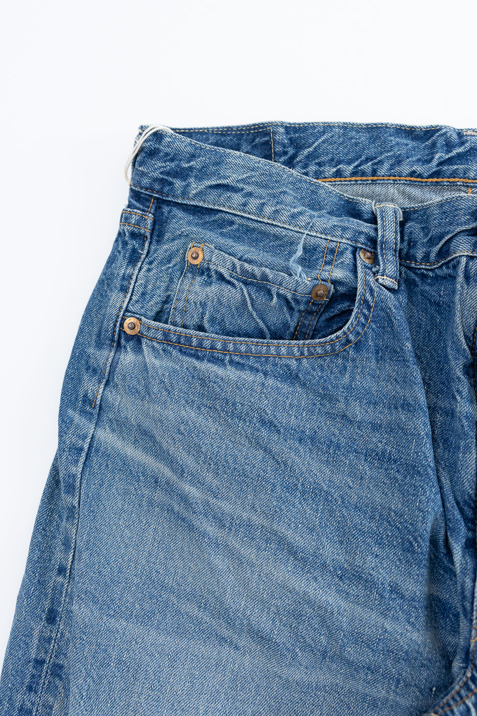 Close-up of Lot 2nd-Hand 1105 - 12oz Used Washed Indigo Denim - Tapered Fit, showcasing waistband, belt loops, front pockets with copper rivets, and prominent top-stitching on lightly faded indigo selvedge denim.