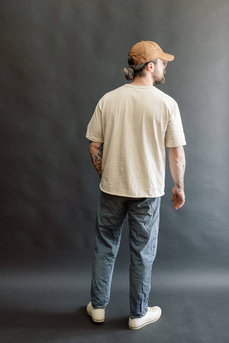 Model wearing Lot 2nd-Hand 1105 - 12oz Used Washed Indigo Denim - Tapered Fit, showcasing vintage-wash blue jeans with a slightly higher rise and relaxed waist, paired with a light-beige T-shirt.