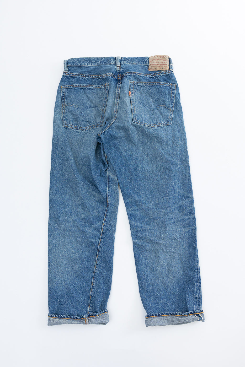 Lot 2nd-Hand 1105 - 12oz Used Washed Indigo Denim - Tapered Fit jeans laid flat, showcasing back pockets, leather brand patch, and rolled cuffs, embodying a 1960s tapered silhouette with authentic aged appearance.