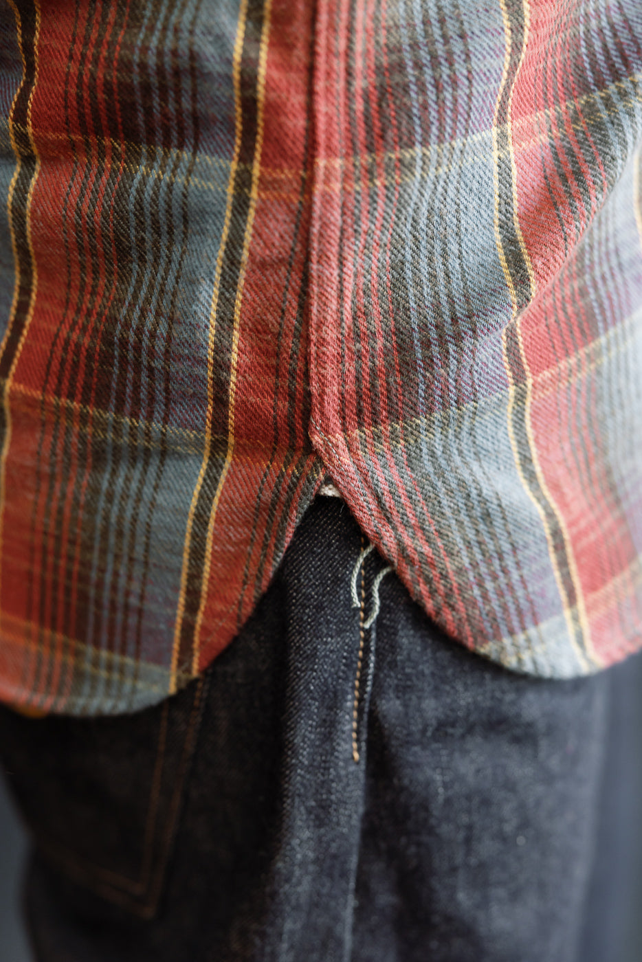 Close-up of the Warehouse & Co. Lot 3022 Flannel Shirt w/ Chinstrap G Pattern, showcasing its red/navy plaid hem overlapping dark denim jeans, highlighting its heritage-inspired design and detailed craftsmanship.