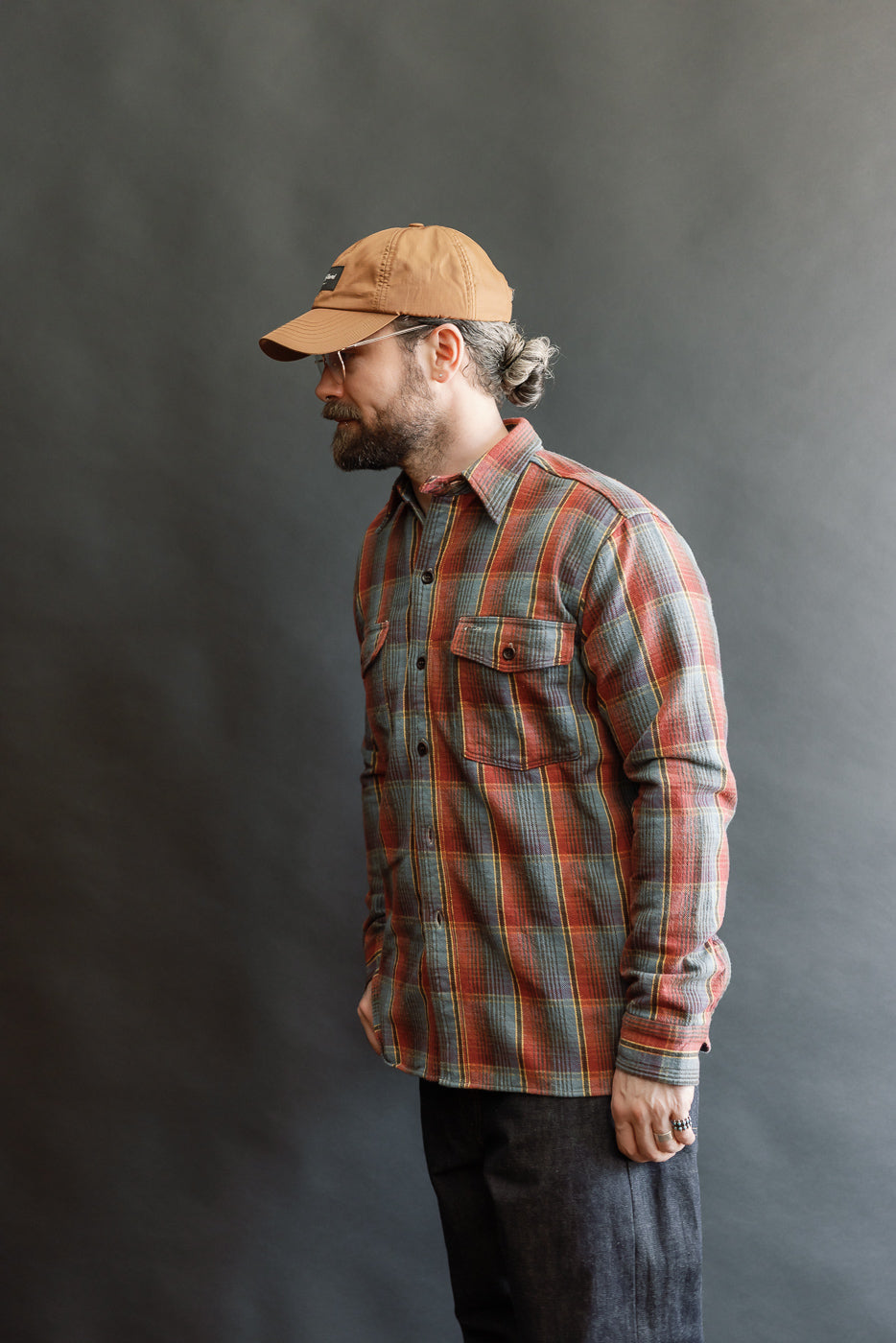 Side-profile of a man wearing the Lot 3022 - Flannel Shirt w/ Chinstrap G Pattern, showcasing its vintage-inspired plaid design, button-flap chest pockets, and distinctive chinstrap closure.