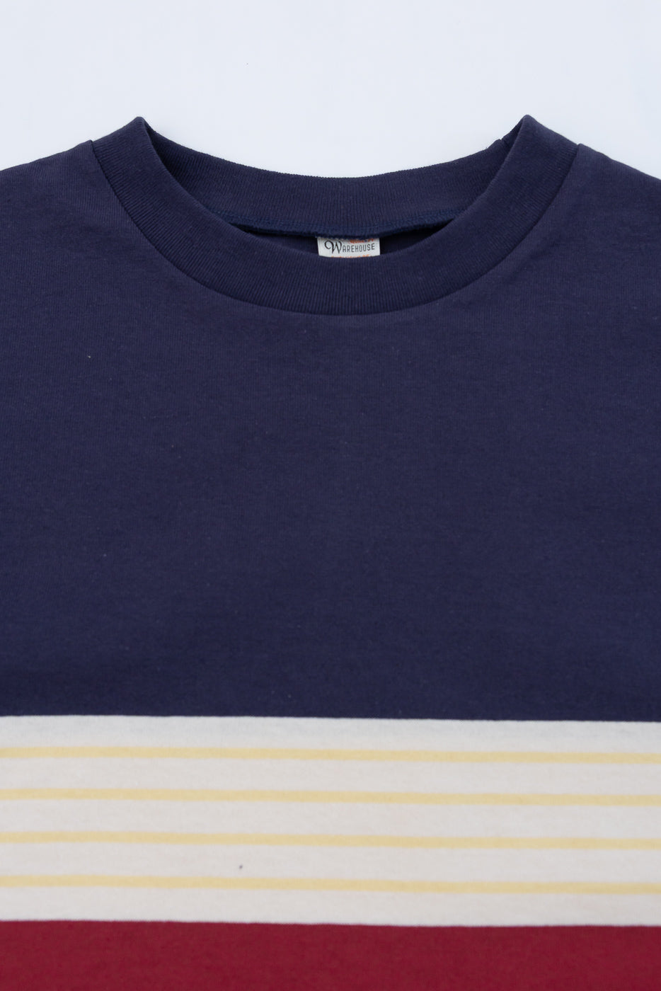 Close-up of the front neckline and tag of a navy blue striped t-shirt.