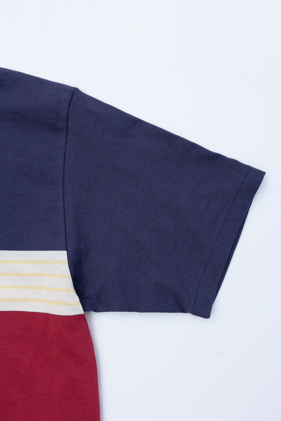 Close-up of the right sleeve and navy blue fabric texture of a color-block t-shirt.