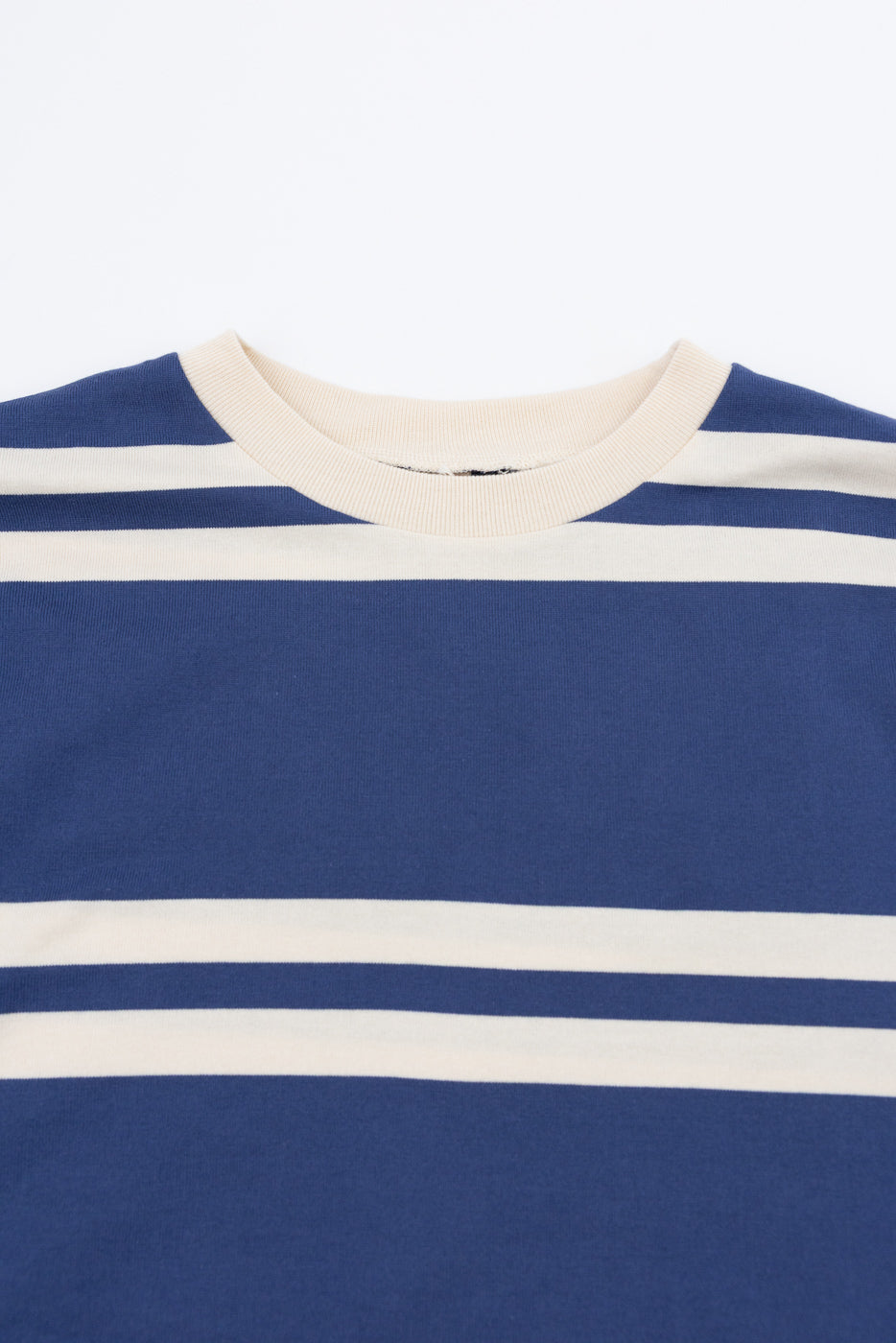 Close-up front view of navy and cream striped crewneck tee, showing ribbed collar and fabric texture