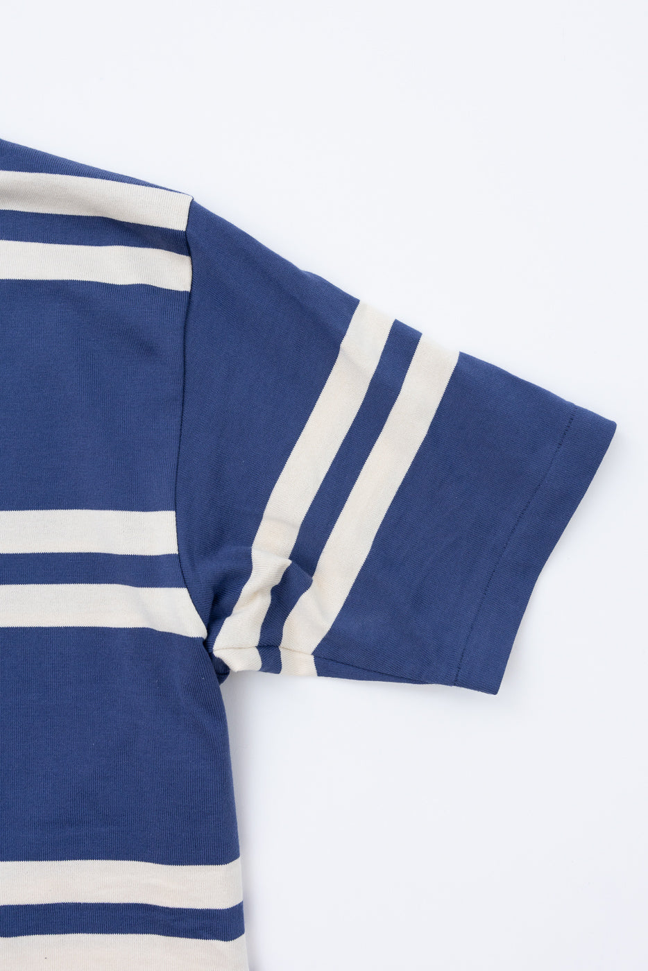 Close-up front view of navy and cream striped short-sleeve tee, showing sleeve hem and ribbed texture