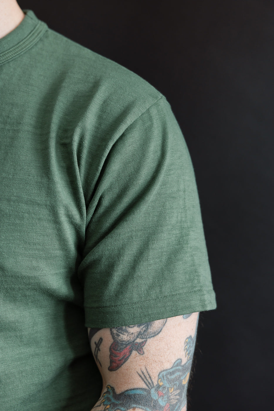 Close-up of right side chest and sleeve on green slubby cotton t-shirt worn by male model, 5'9
